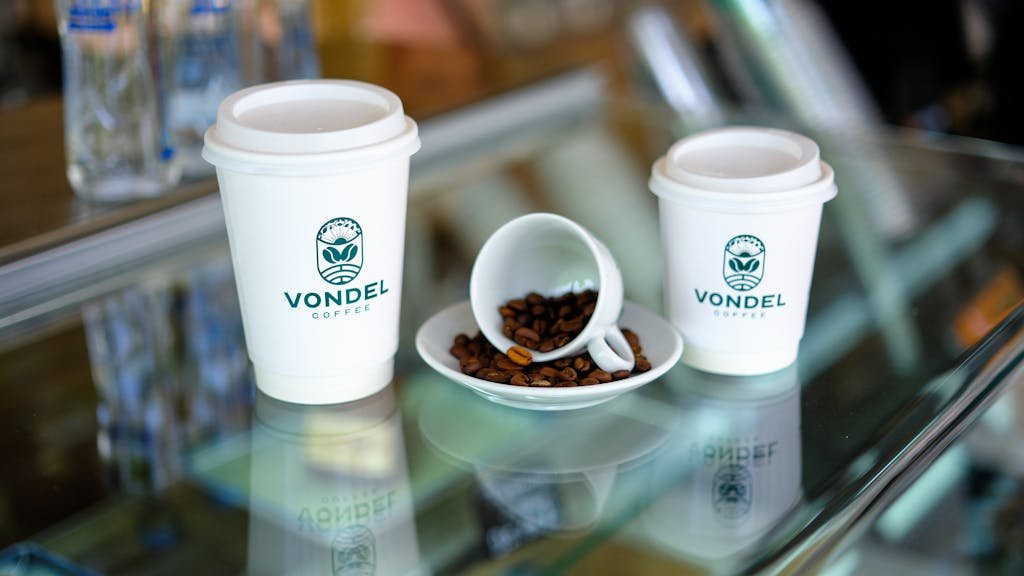 Two coffee cups sit on a glass table