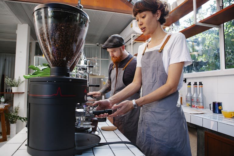 Crop baristas preparing coffee in cafe kitchen