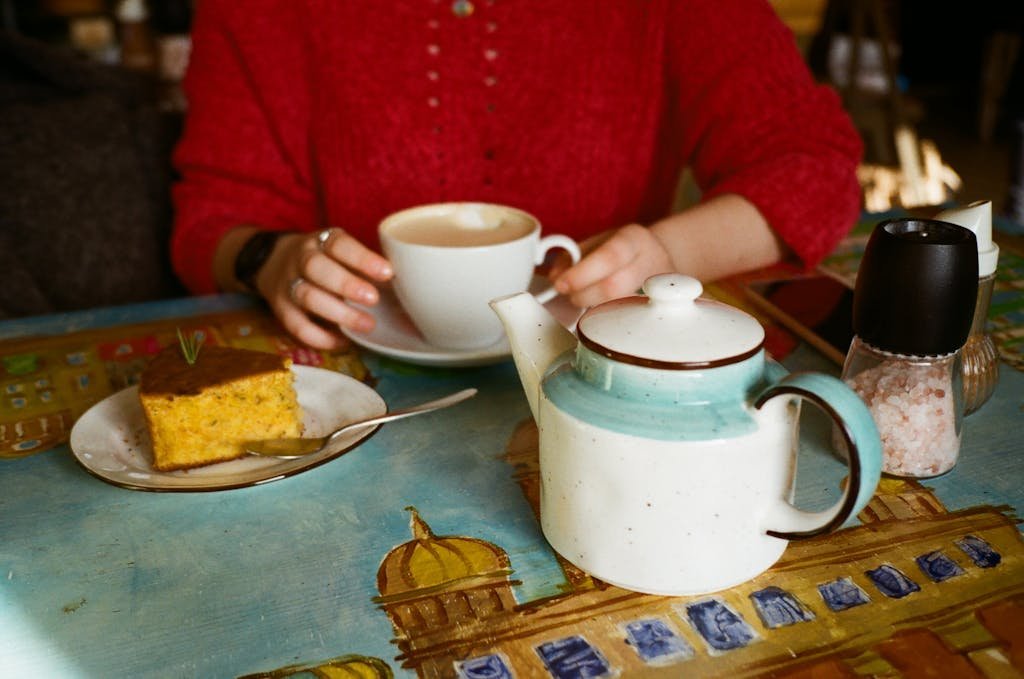 Unrecognizable woman with coffee and delicious cake in cafe